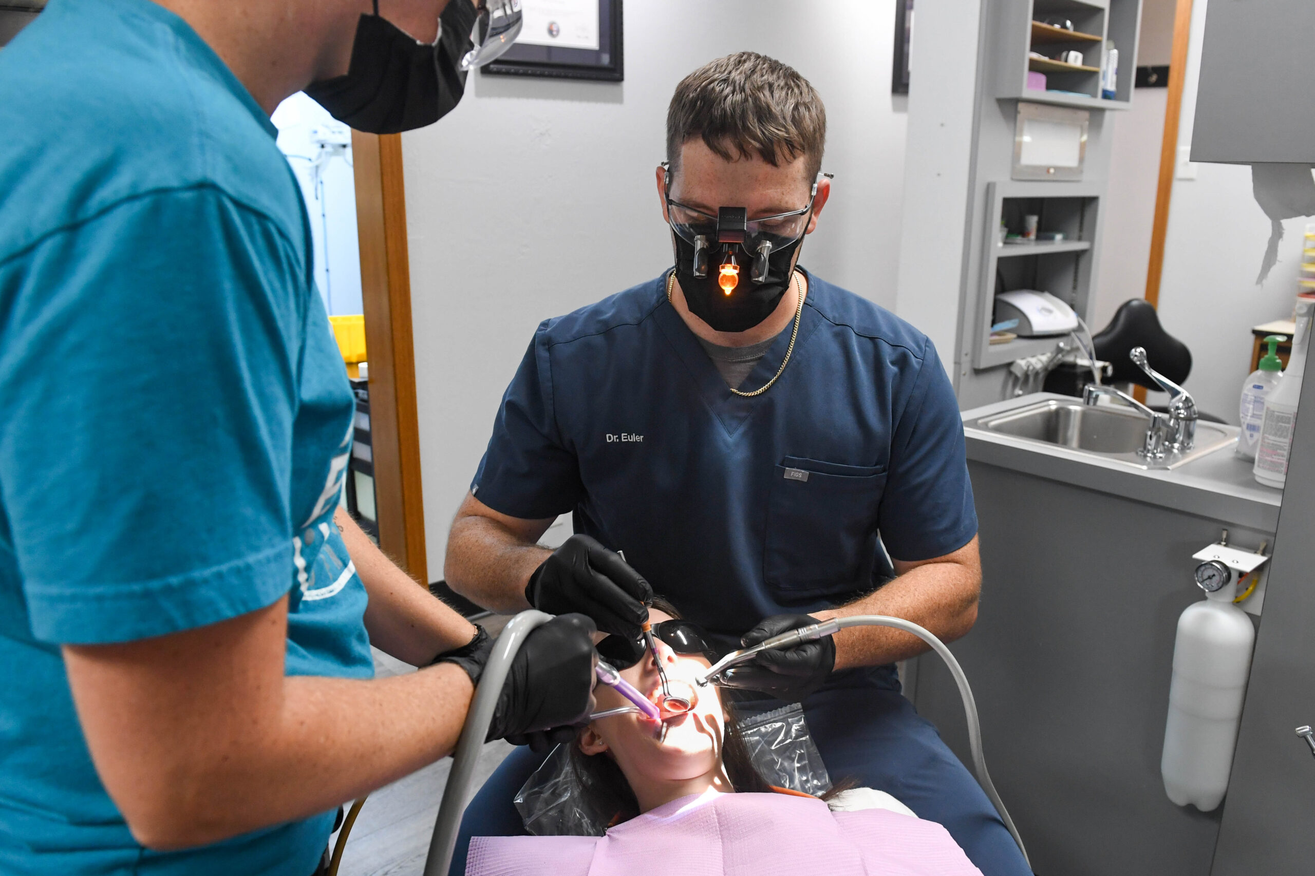 Dr. Euler and another dentist holding tools working on a patient